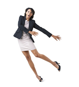 Accident-prone female executive falling over against a white background
